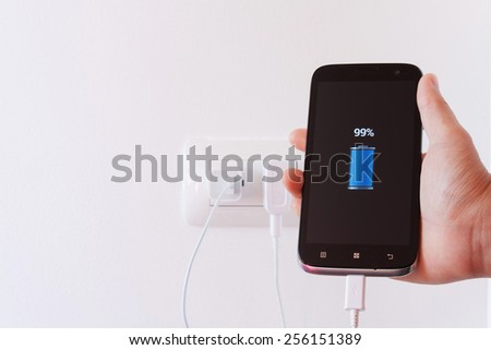 female hand plugging in the wall electtric plug of her smartphone in a socket.Power is not enough for human Stock photo © 