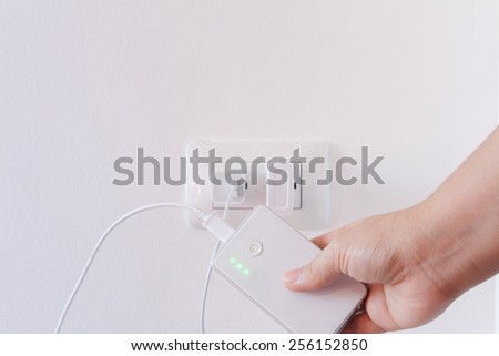 female hand plugging in the wall electtric plug of her power bank in a socket Stock photo © 