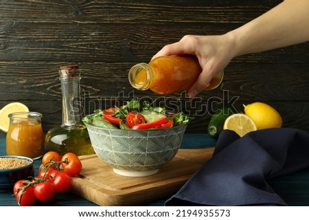 Female hand pour honey mustard sauce on salad