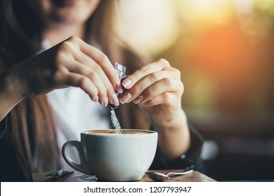 Female hand pours sugar into coffee. Sunlight background - Powered by Shutterstock