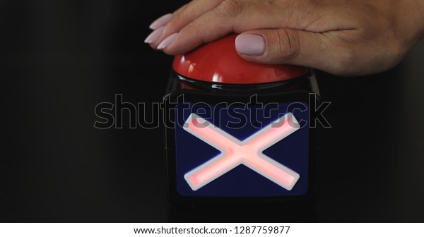 Female hand presses the stop button. Big\
red button with stop inscription being\
pushed. 