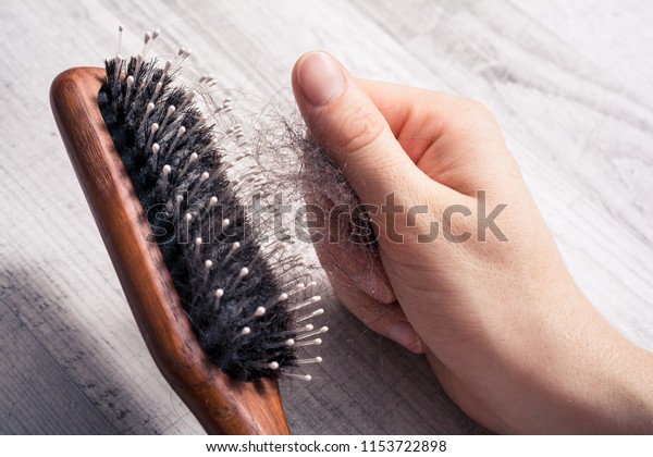 Female Hand Pulling Bunch Of Hair Out Of Brush -\
Alopecia Hair Loss\
Concept