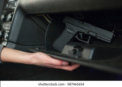 The Female Hand Pulls Out A Gun From The Glove Box In The Car