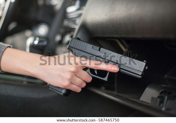 The female hand pulls out a gun from the glove box in\
the car