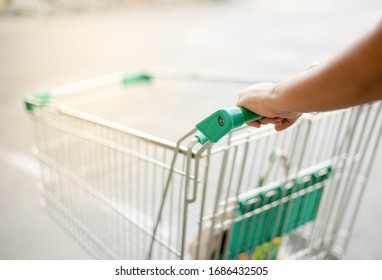 Female hand pushing shopping trolleys in Supermarket Walking through the Aisle preparing food for the hoarding food coronavirus (COVID-19) pandemic crisis. 