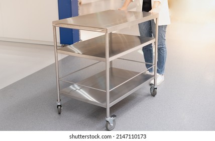 Female Hand Pushing The Stainless Steel Food Trolley Cart To Move A Lot Of Parcels. 