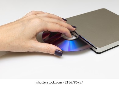 Female Hand Puts A Laser Disc Into The Drive. High Quality Photo