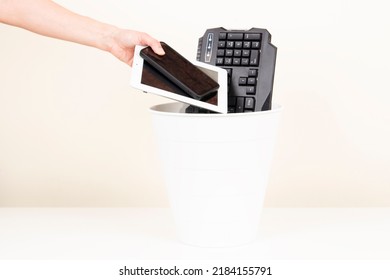 Female Hand Puts Used Digital Tablet Computer And Cell Phones Into Recycling Bin Full Of Old Electronic Devices. Planned Obsolescence, E-waste, Electronics Waste For Reuse And Recycle Concept