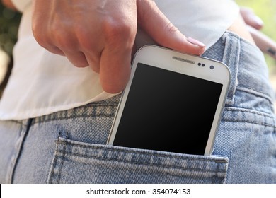 Female hand puts white smart mobile phone into jeans pocket