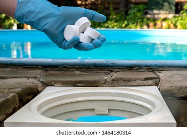 Female hand puts white tablets into pool skimmer. Cleaning, disinfection of water in the swimming pool. - Powered by Shutterstock