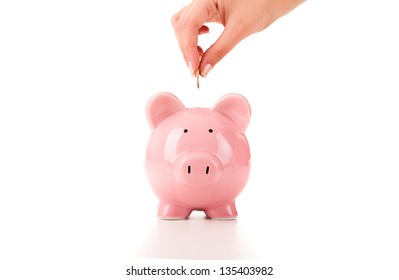 Female hand putting a coin into piggy bank