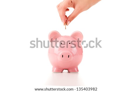 Female hand putting a coin into piggy bank