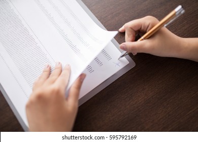 Female hand putting signature on financial report - Shutterstock ID 595792169