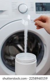 Female hand putting washing powder. Washing linen and clothes idea. Correct use of the washing machine concept. New washing machine standing in a modern bathroom. - Shutterstock ID 2258960159