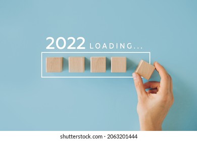 Female hand putting wooden cube for countdown to 2022. Loading year from 2021 to 2022. New year start concept