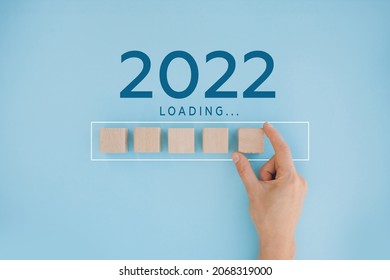Female hand putting wooden cube for countdown to 2022. Loading year from 2021 to 2022. New year start concept