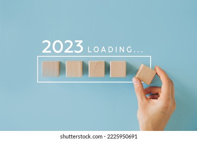 Female hand putting wooden cube for countdown to 2022. Loading year from 2022 to 2023. New year start concept
