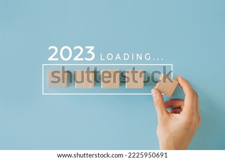 Female hand putting wooden cube for countdown to 2022. Loading year from 2022 to 2023. New year start concept