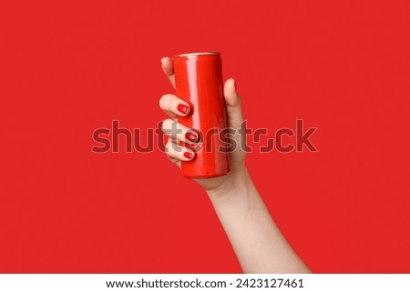 Female hand with red manicure holding can on color background