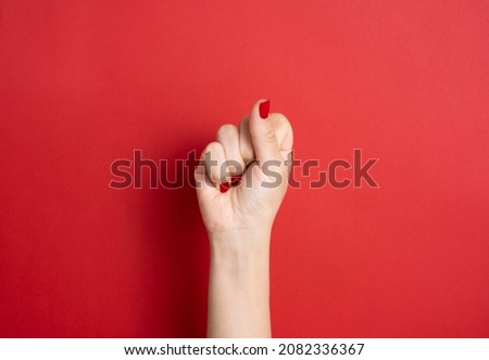 Female hand with red nails on red background, women's day , female power