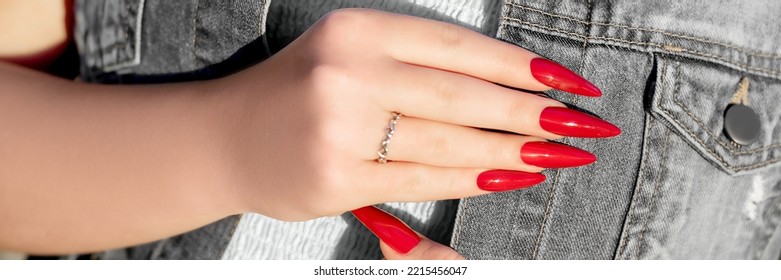 Female hand with red stiletto nail design. Glitter red nail polish manicure. Young female model with perfect red stiletto nail design. Advertising banner template. Horizontal banner ad.