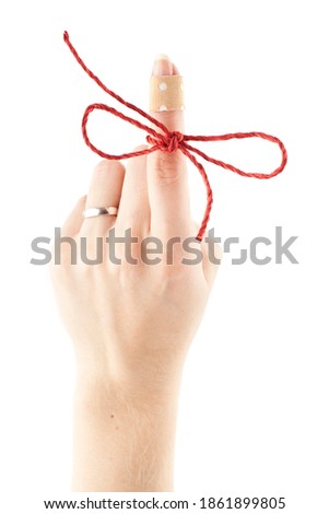 Female hand with a red string tied to the index finger. 