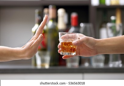 Female hand rejecting glass with alcoholic beverage on blurred background