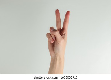 Female hand shows gesture v symbol on a white background