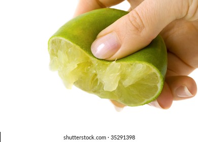 Female hand squeezing juice from a green lime. Isolated on white background.