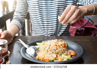 Female Hand Squeezing Lime On Fried Rice Meal