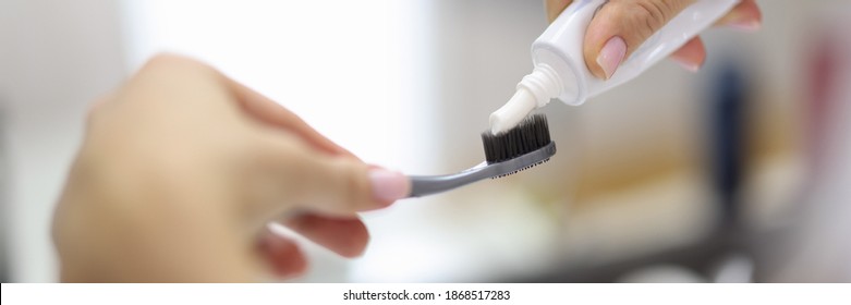 Female Hand Squeezing Toothpaste From Tube Onto Toothbrush Close-up. Daily Oral Care After Meals Concept.