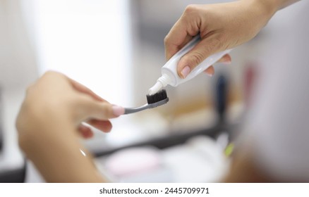 Female hand squeezing toothpaste from tube onto toothbrush close-up. Daily oral care after meals concept. - Powered by Shutterstock