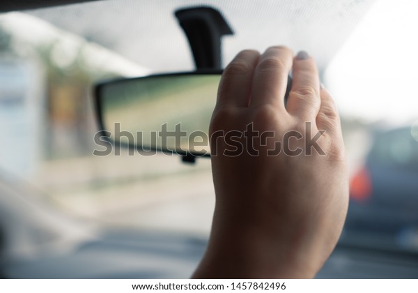 Female\
hand straightens the mirror in the car to see herself and fix the\
makeup. Concept of woman driving. Female\
driver