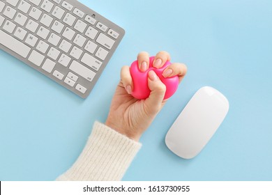 Female hand with stress ball, computer keyboard and mouse on color background