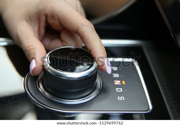 the female driver’s hand switches the\
automatic transmission joystick to\
neutral