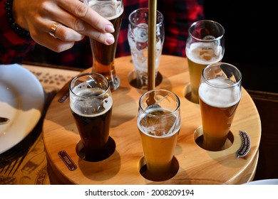 Female hand takes glass of craft beer in pub to make toast cheers. Drinking various types of craft beer including stout, lager, ale, pilsner and weiss. People enjoying beer
