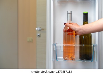 Female Hand Taking Bottle Of Wine From A Fridge