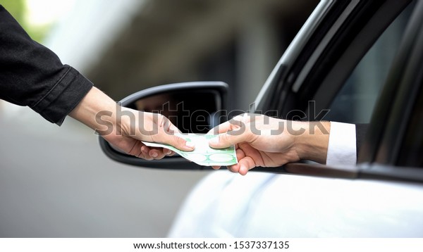 Female hand taking euro banknote from driver hand,\
autobahn payment, order