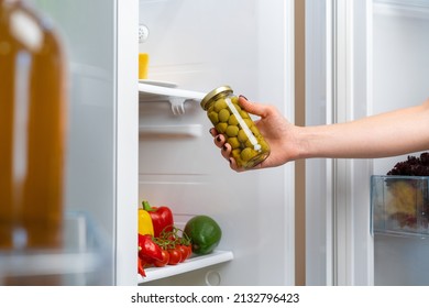 Female Hand Taking Jar Of Olives From A Fridge