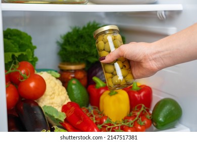 Female Hand Taking Jar Of Olives From A Fridge