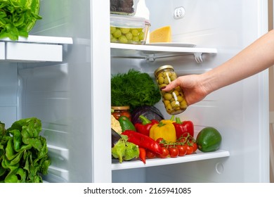 Female Hand Taking Jar Of Olives From A Fridge