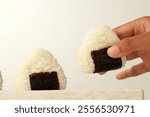 Female Hand Taking Onigiri Japanese Rice with Triangle Shape and Nori 