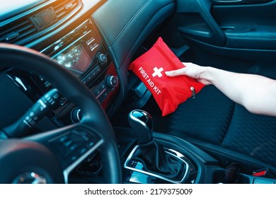 Female hand taking red first aid kit from the car glove box. A well-equipped car for road trips concept. - Shutterstock ID 2179375009