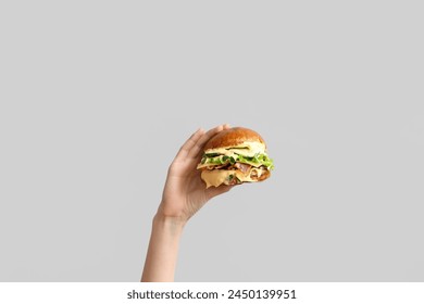 Female hand with tasty burger on white background