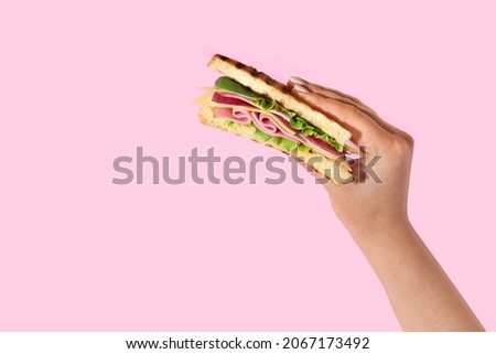 Female hand with tasty sandwich on color background