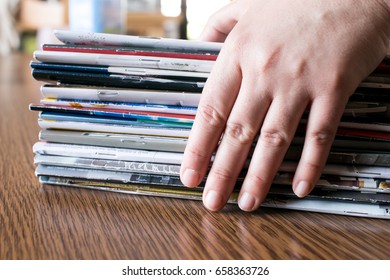 Female Hand that is taking a stack of magazines on wooden table
