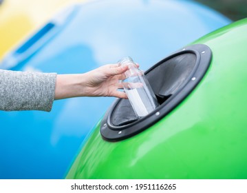 Female Hand Throwing Empty Glass Bottle Into Yellow Recycle Bin Container Outdoors, Unrecognizable Woman Enjoying Waste Sorting Ang Garbage Recycling, Cropped Image With Selective Focus, Closeup