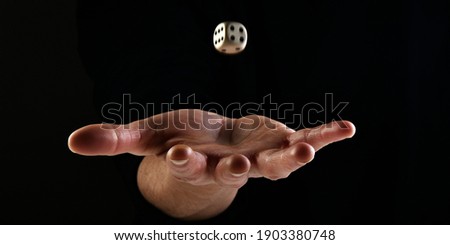 Female hand throwing one dice in the air on black background. Gambling luck concept: bet, risk, have luck, win. Fortune concept playing dice