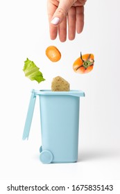 Female Hand Throws Organic Trash Into Trash Can, White Background