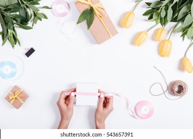 Female Hand Tied Ribbon Box With A Gift On White Table, Top View